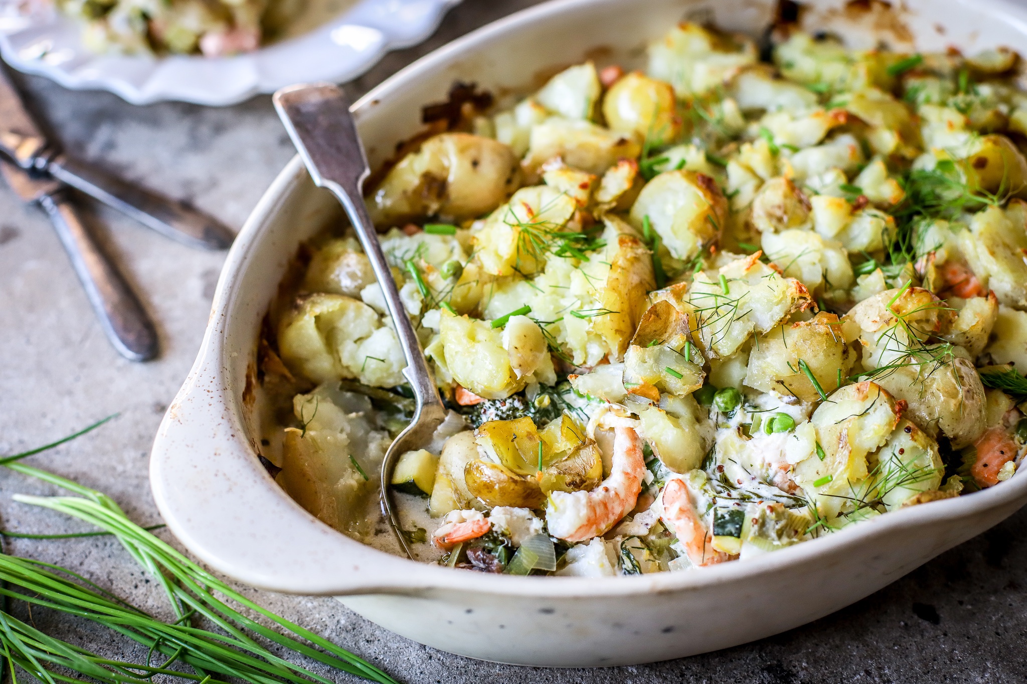 summer fish and vegetable pie side view with spoon in